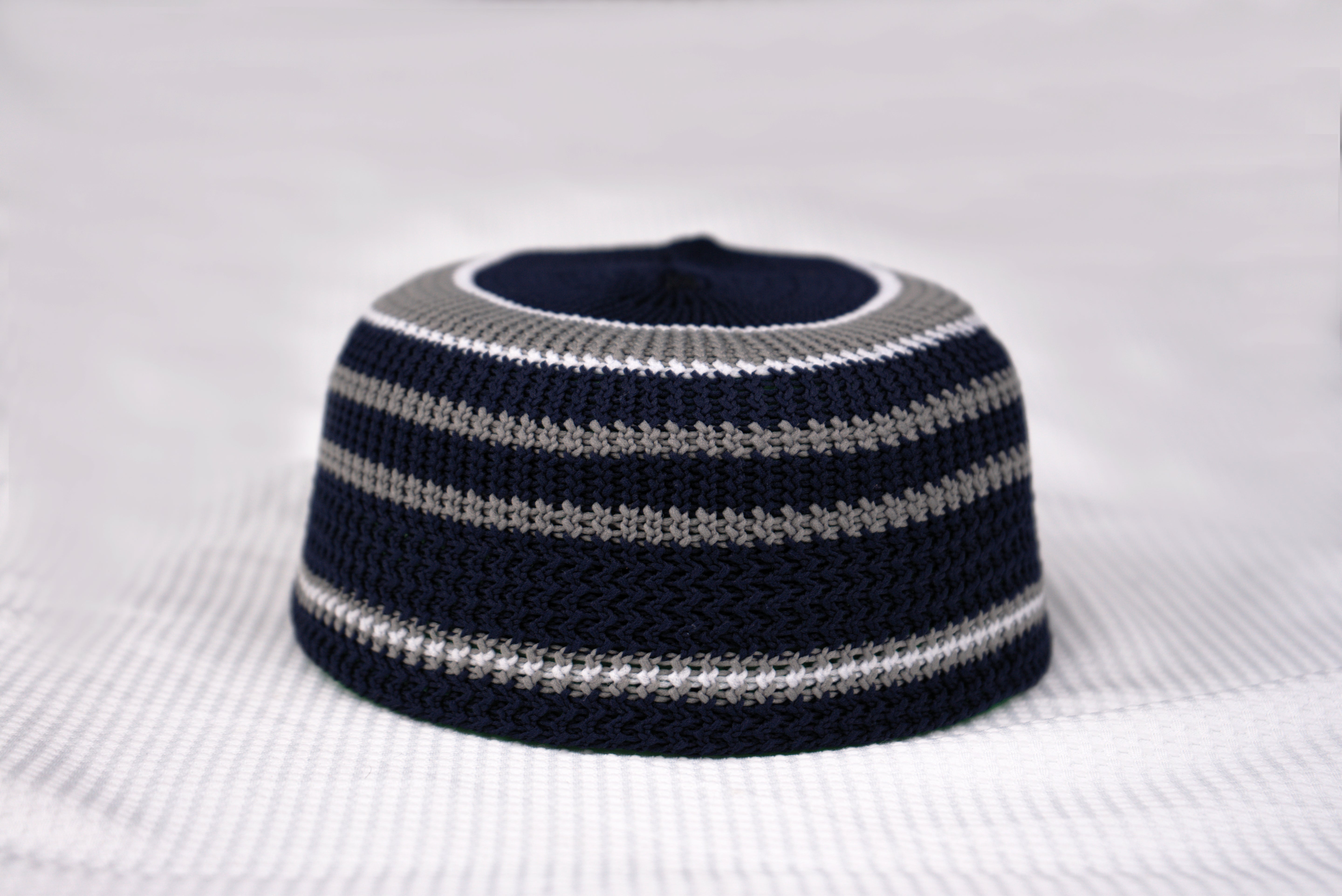Navy and gray striped knitted hat on a white background