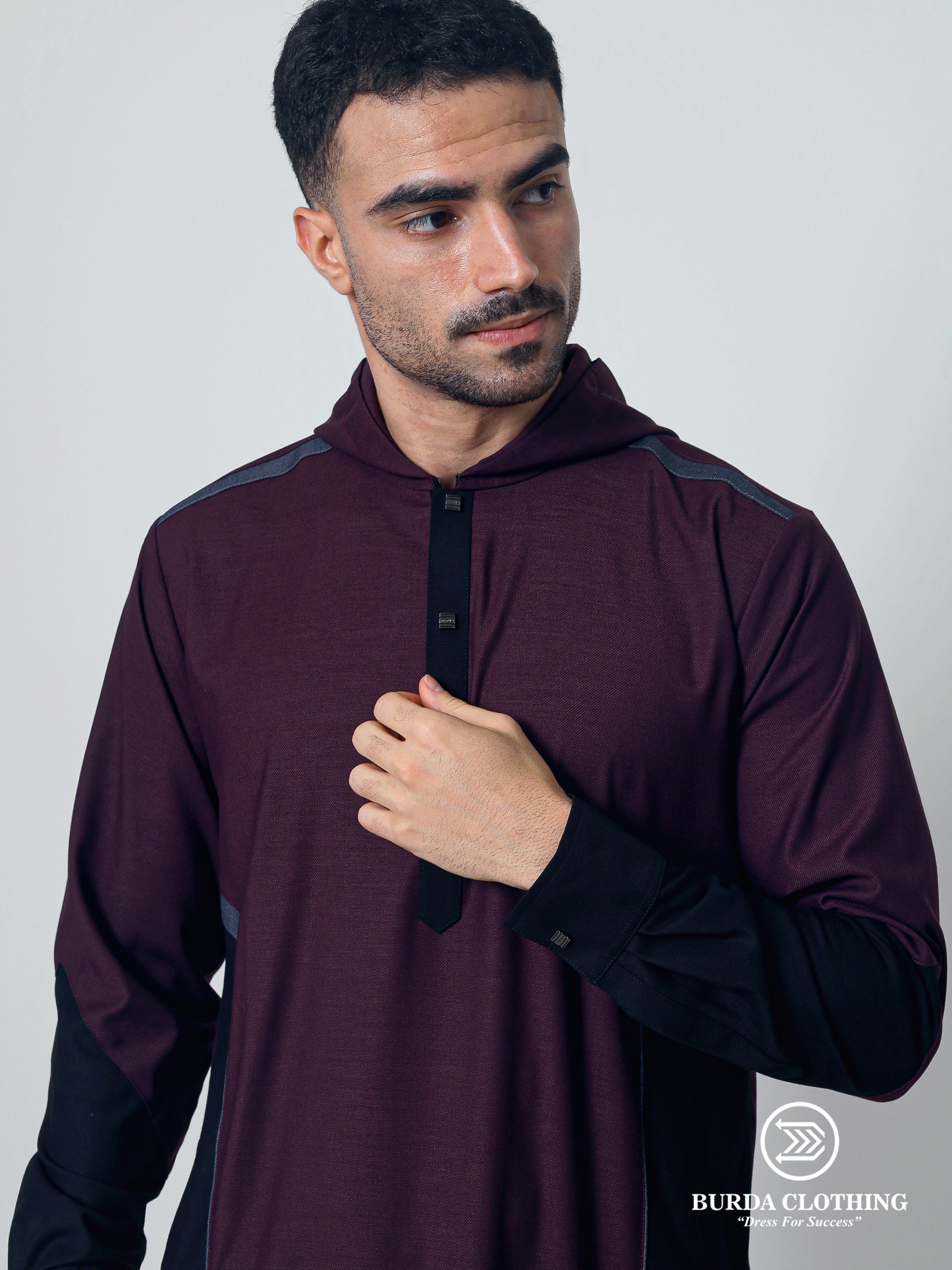 Man wearing a maroon hoodie with black sleeves against a plain background, featuring the Burda Clothing brand.
